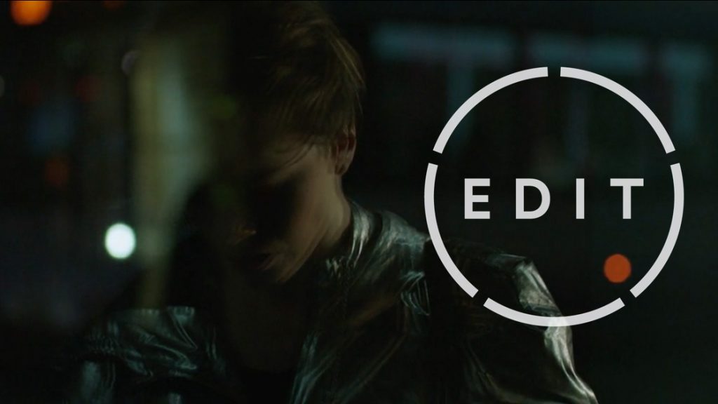 A figure with reddish-blonde hair in a metallic jacket beside a circular "EDIT" logo.
